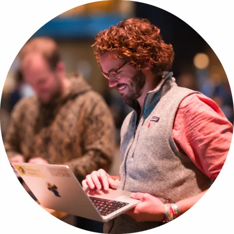 Joost werkt aan een laptop, met iemand op de achtergrond